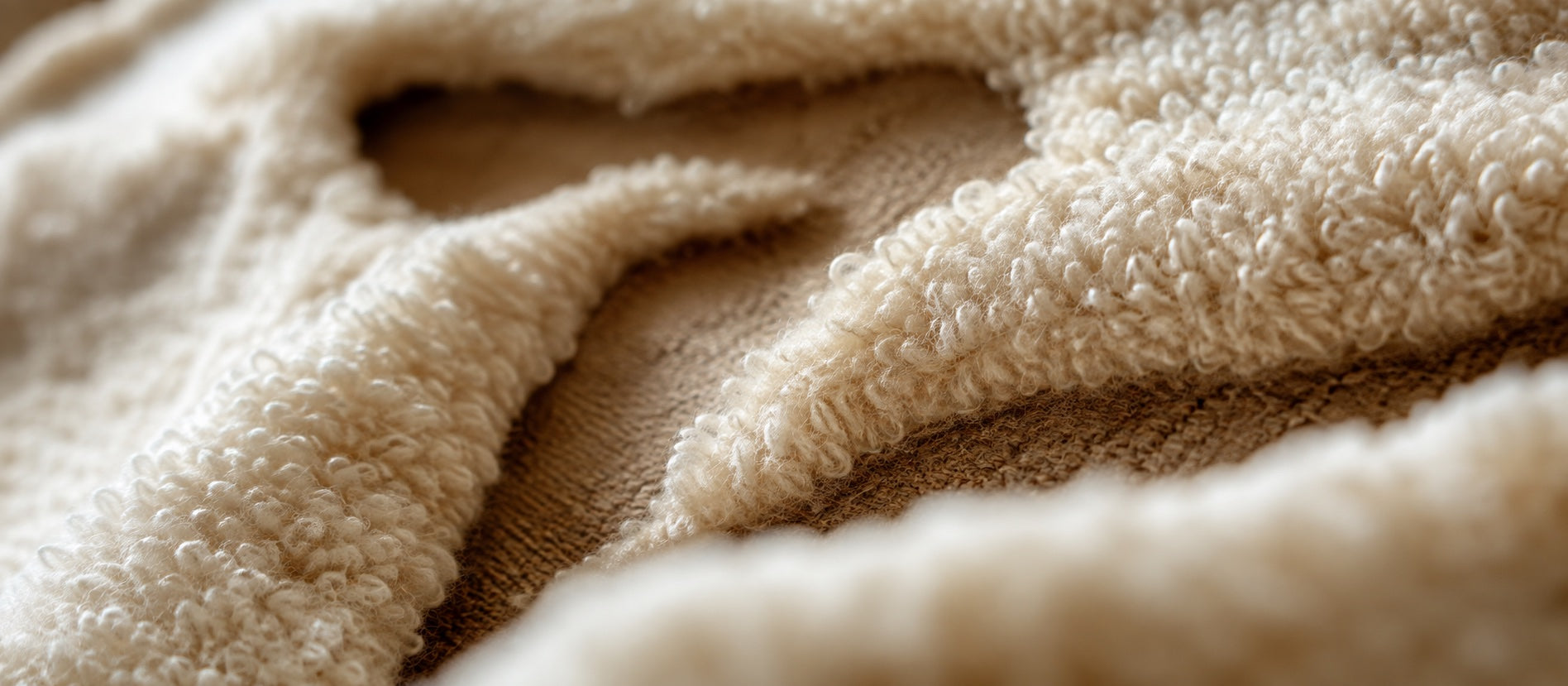 Side-angle macro of carved cream wool relief showing its raised pile and woven ground