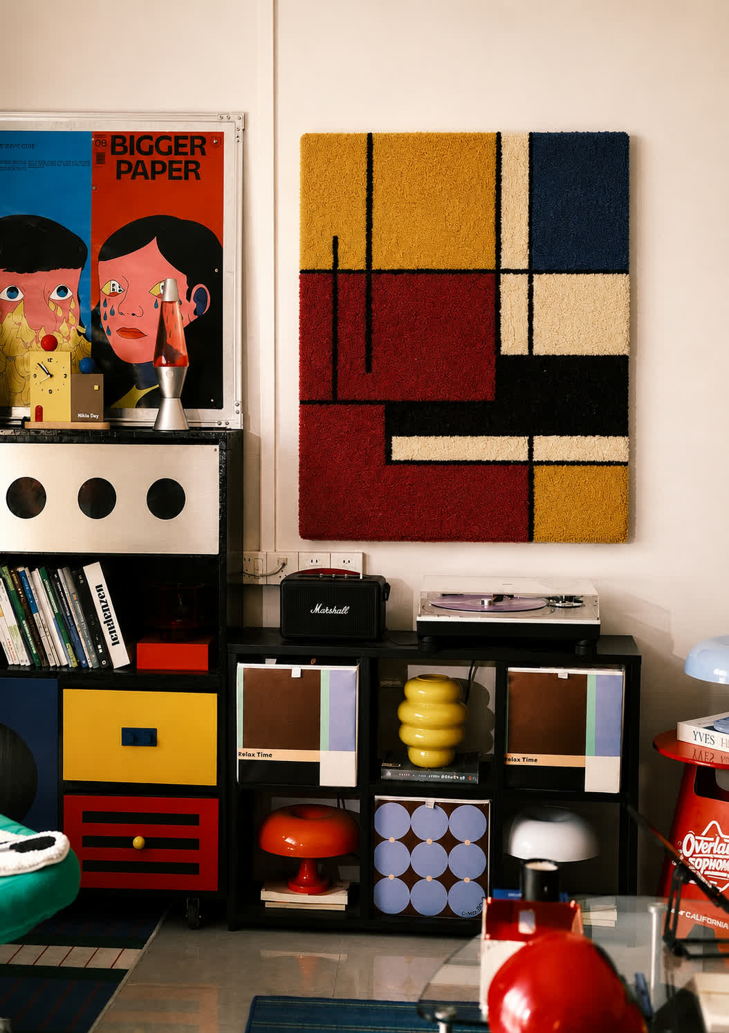 A hand-tufted wool De Stijl grid panel in mustard, red, navy and cream hung above a record player in a collector's room