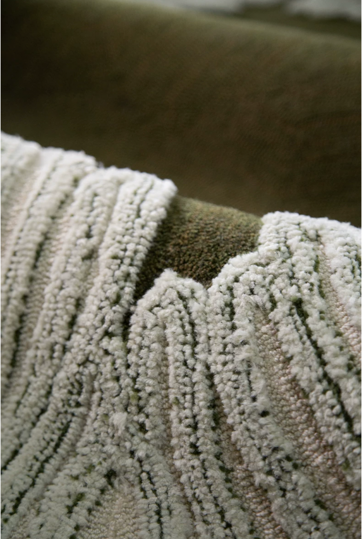 Close-up of Hewn Earth Studio's Camellia moss bloom rug featuring intricate pattern and soft green tones in a macro view.