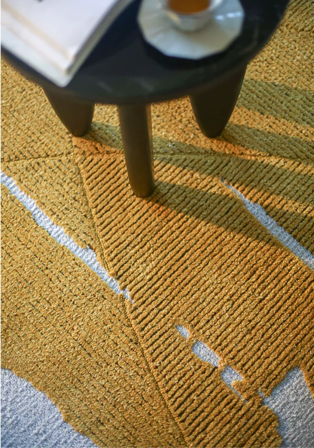 Gold leaf foil rug by Hewn Earth Studio with a shiny, metallic surface and intricate textured design.