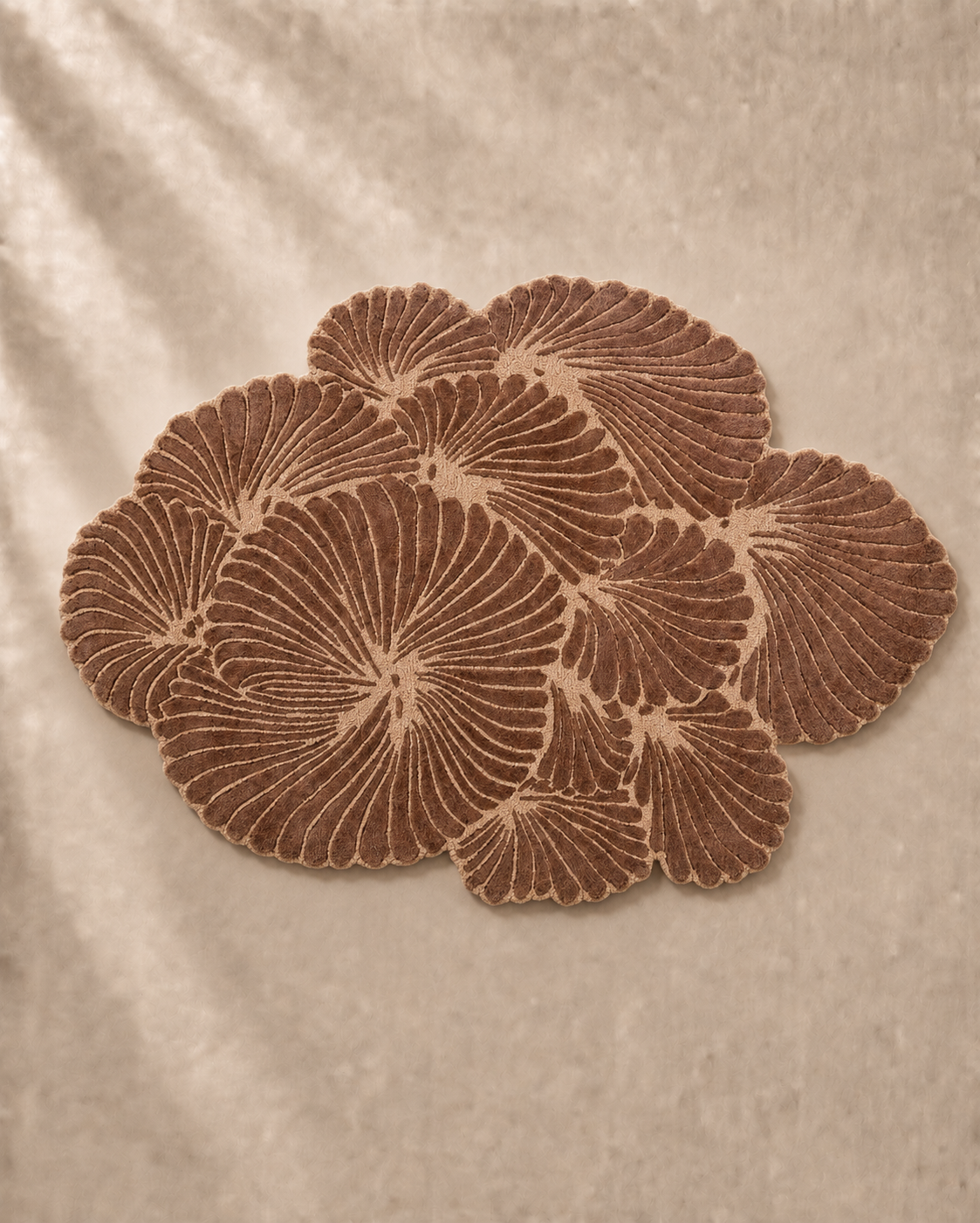 Hewn Earth Studio Frond rug in cocoa color, featuring natural woven texture, shown on wooden floor with feet for size reference.