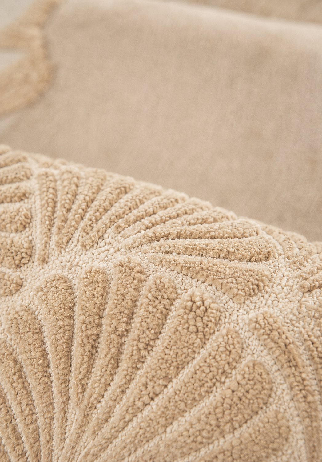 Close-up of Hewn Earth Studio Frond rug in sand color, showcasing detailed woven pattern and natural texture.