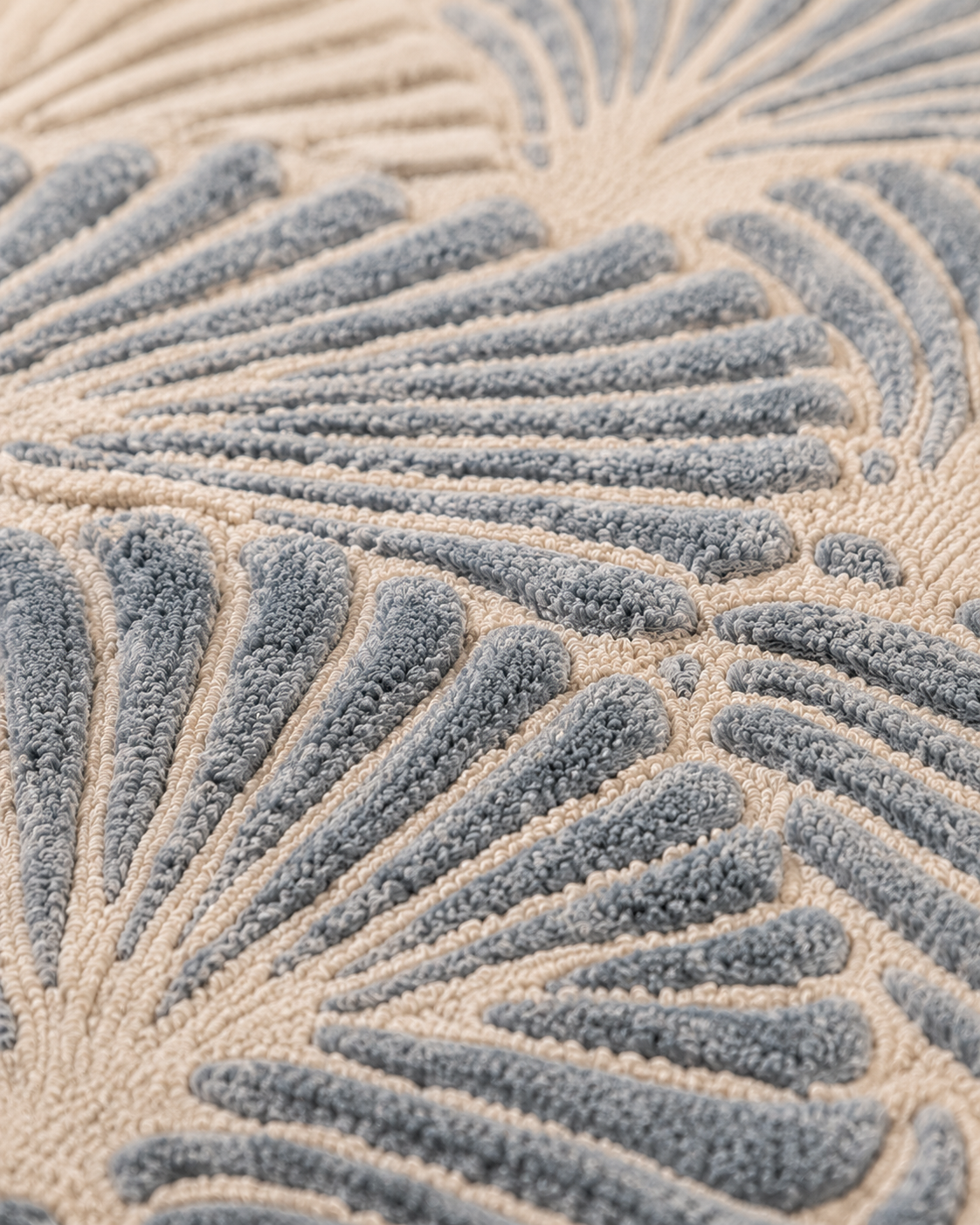 Hewn Earth Studio Frond slate rug with botanical leaf design, textured fabric, placed on a table in a well-lit room.