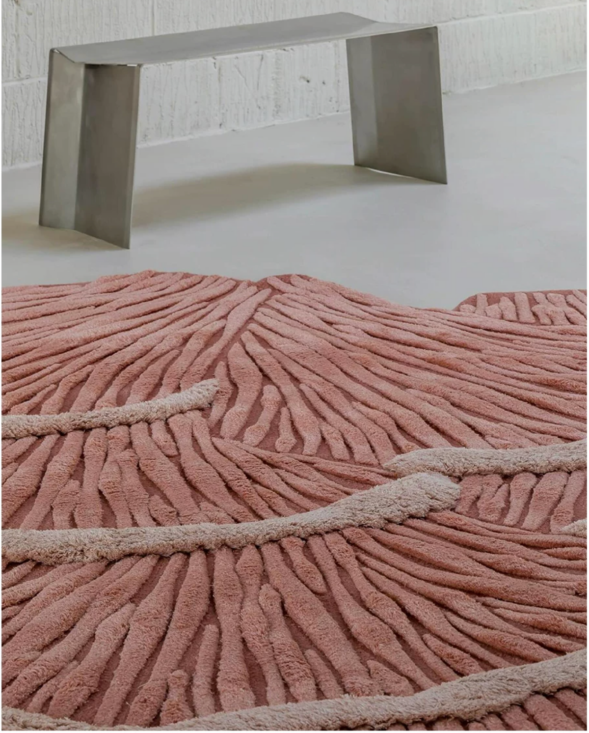 Hewn Earth Studio Palma rug in coral blush with intricate woven pattern, shown as a decorative bench or floor covering.