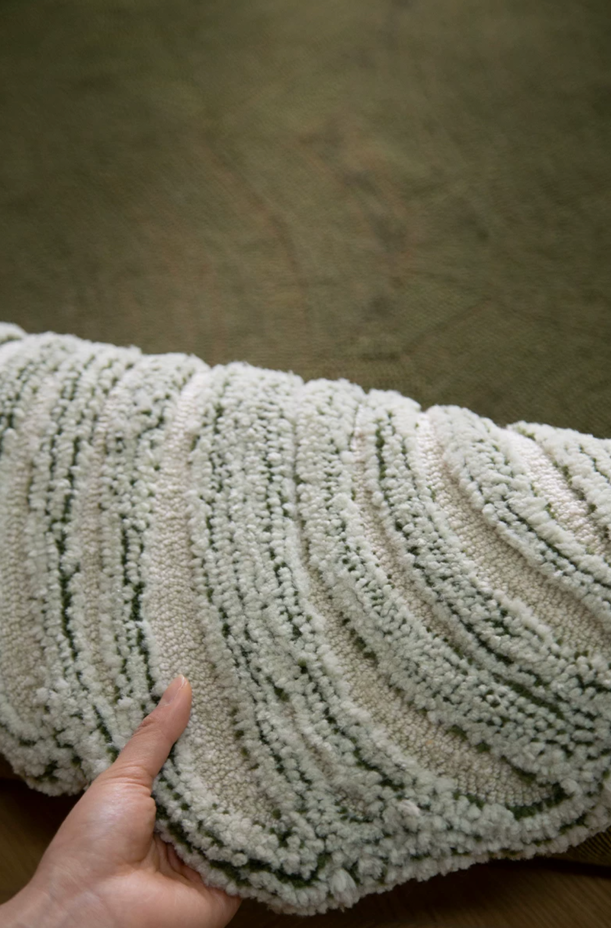 Hewn Earth Studio Camellia moss-colored rug with detailed woven texture and floral-inspired pattern.