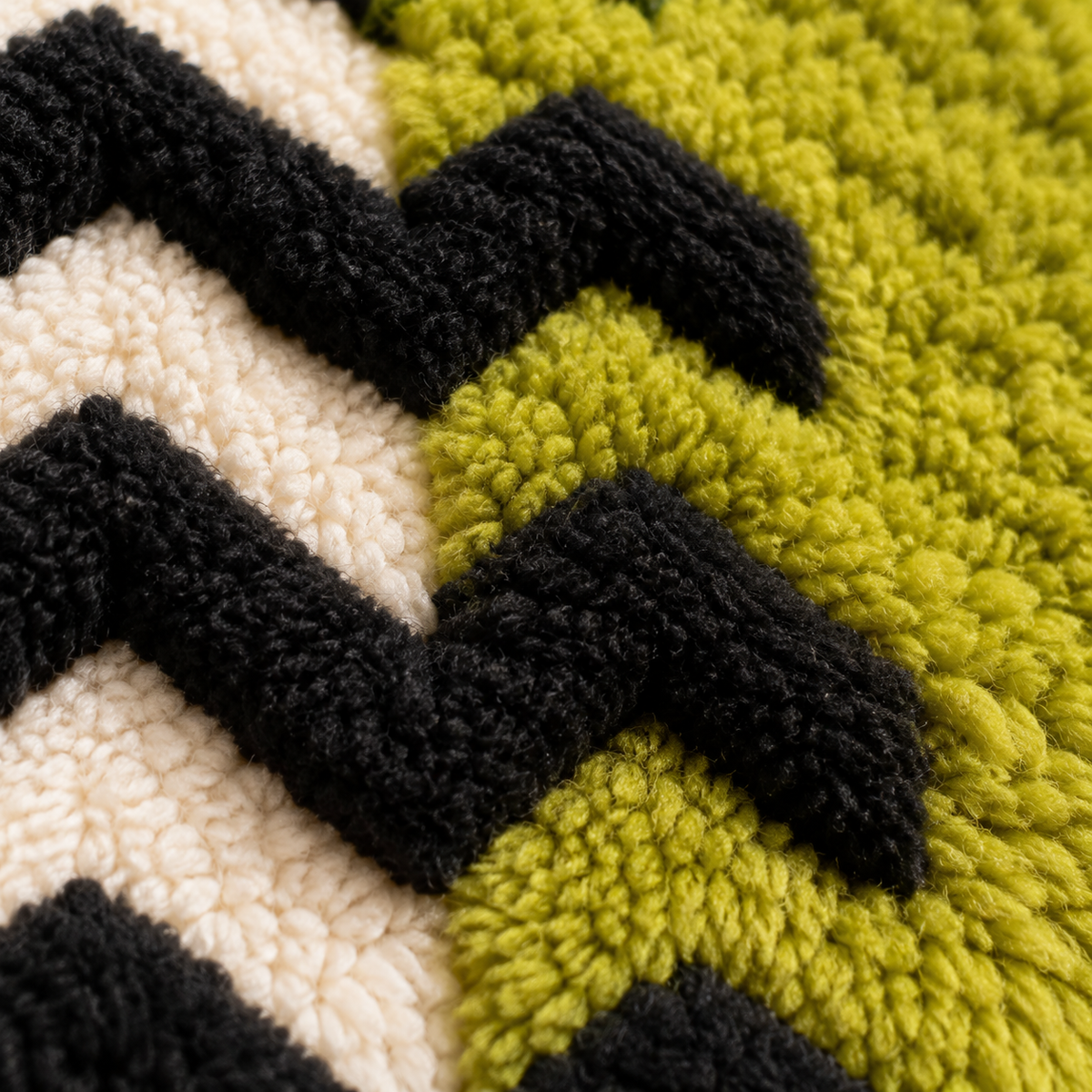 Close-up of Hewn Earth wall art featuring chartreuse field and black chevrons with detailed geometric patterns.