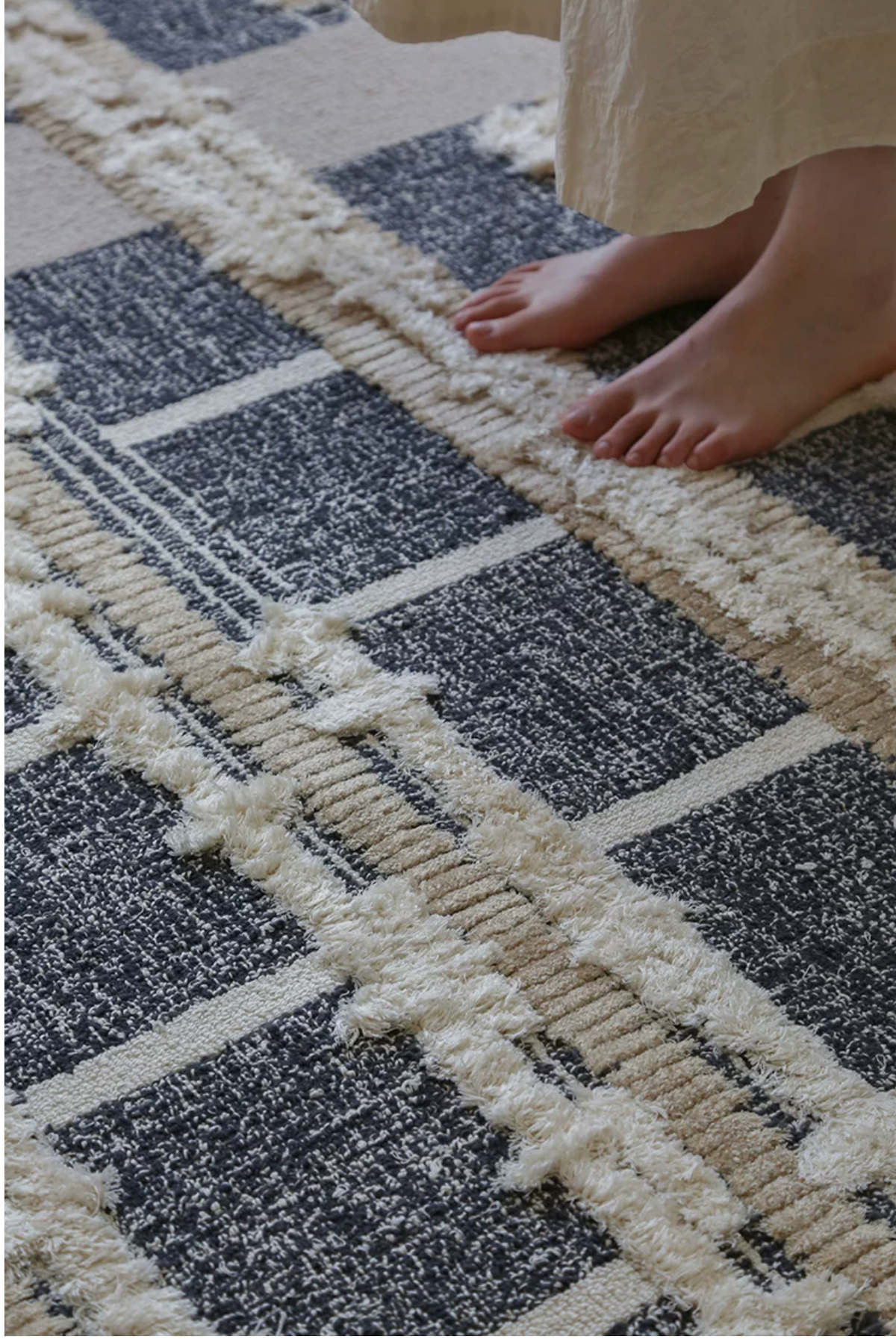Hewn Earth Studio rug with a grid pattern featuring feet design, showcasing geometric lines and textured surface.