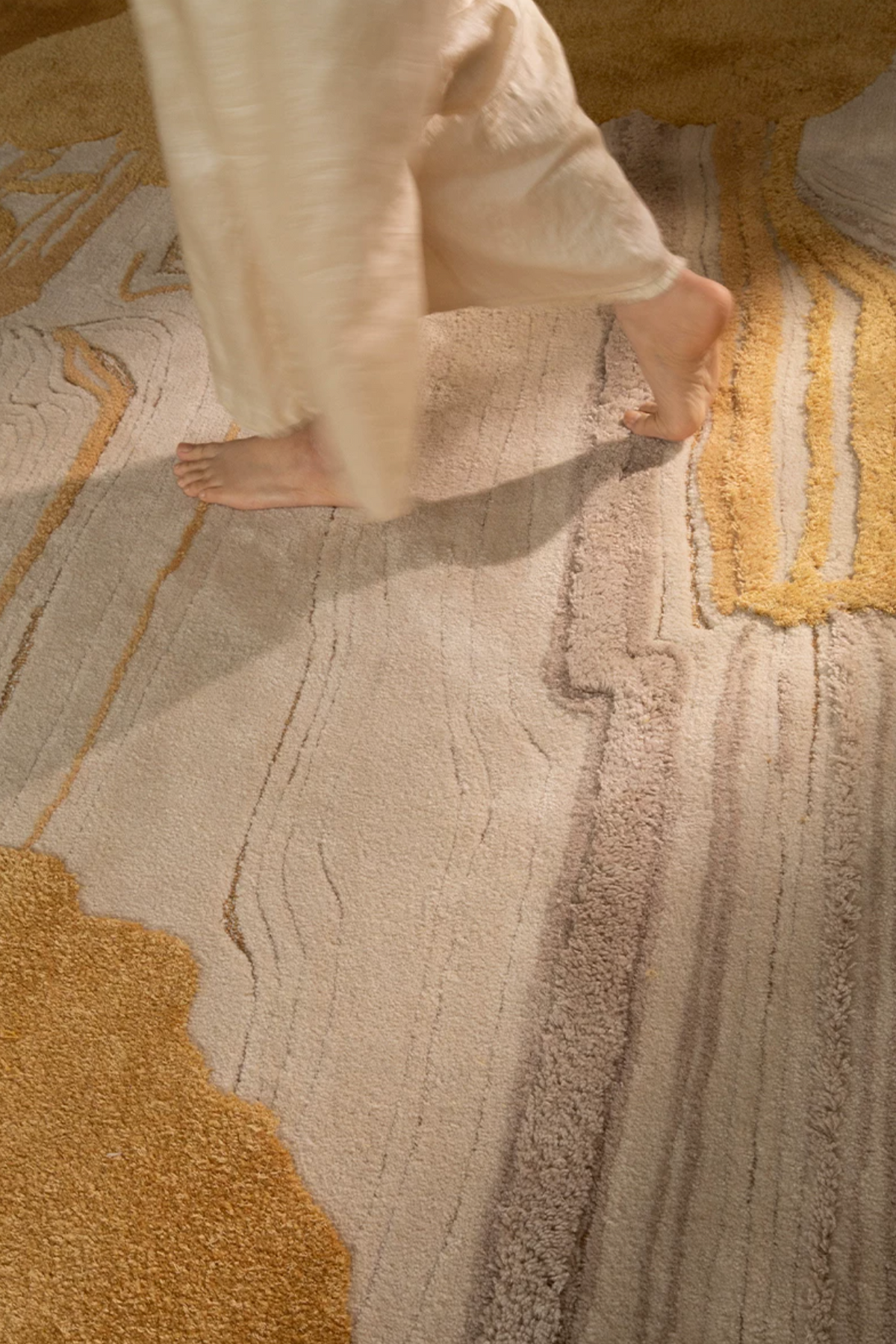 Hewn Earth Studio Lode rug with intricate geometric patterns in neutral tones, displayed on a wooden floor in a cozy room setting.