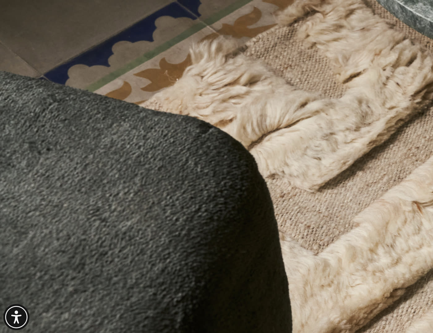 Close-up of a hand-tufted wool rug with plush pile detail on a patterned tile floor