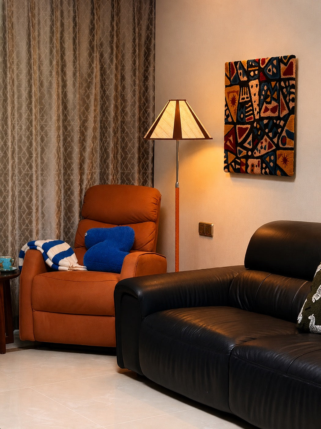 A hand-tufted wool tapestry in rust, ochre and deep blue hung above a leather sofa in a lamplit living room