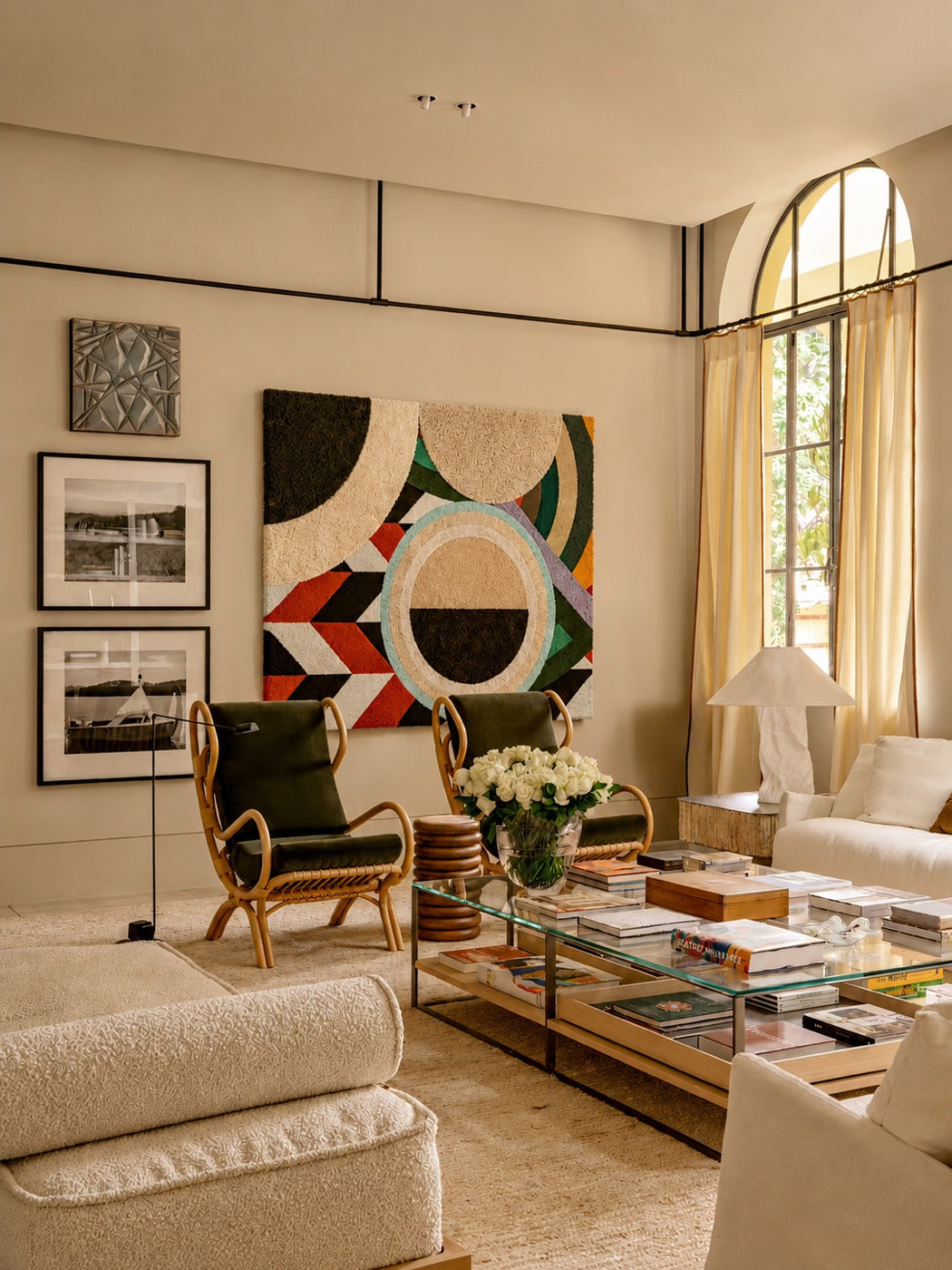 A large hand-tufted wool geometric panel in cream, forest green and orange hung above bentwood chairs in a sunlit arched living room