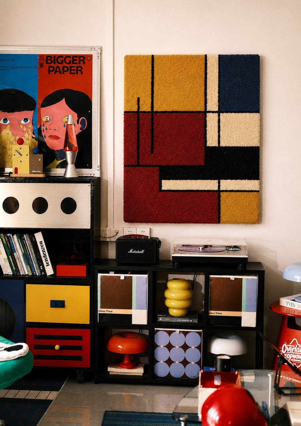 A hand-tufted wool De Stijl grid panel in mustard, red, navy and cream hung above a record player in a collector's room