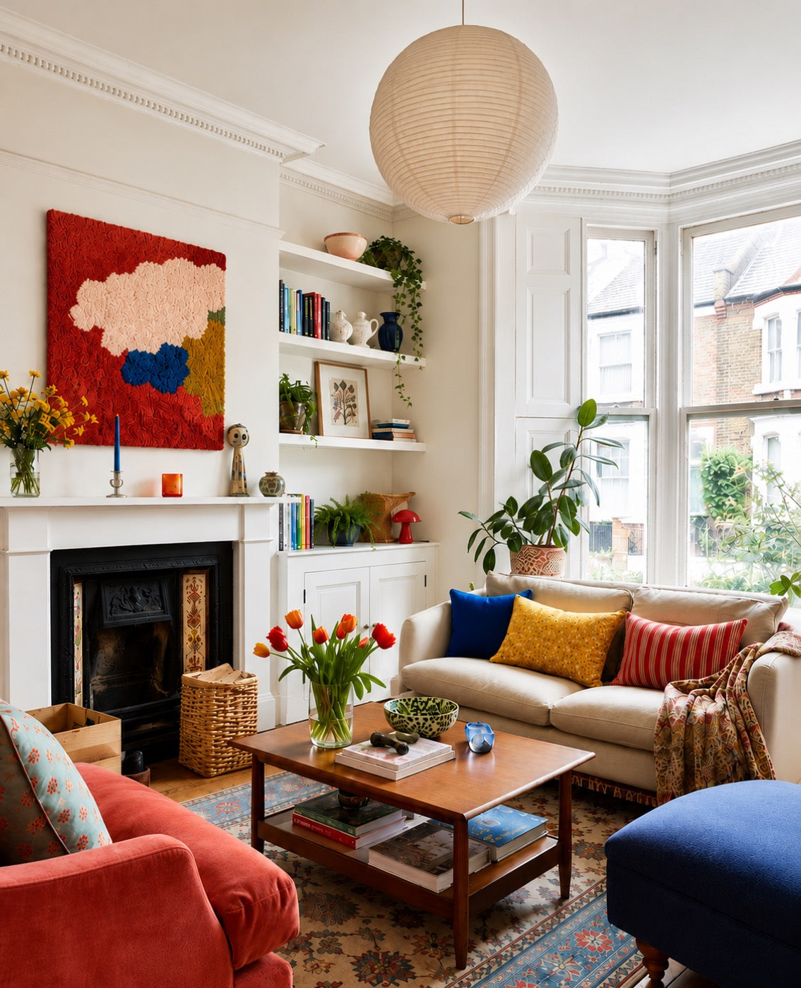 A hand-tufted wool abstract panel in scarlet, blush and cobalt hung above a white mantel in a Victorian bay-window sitting room