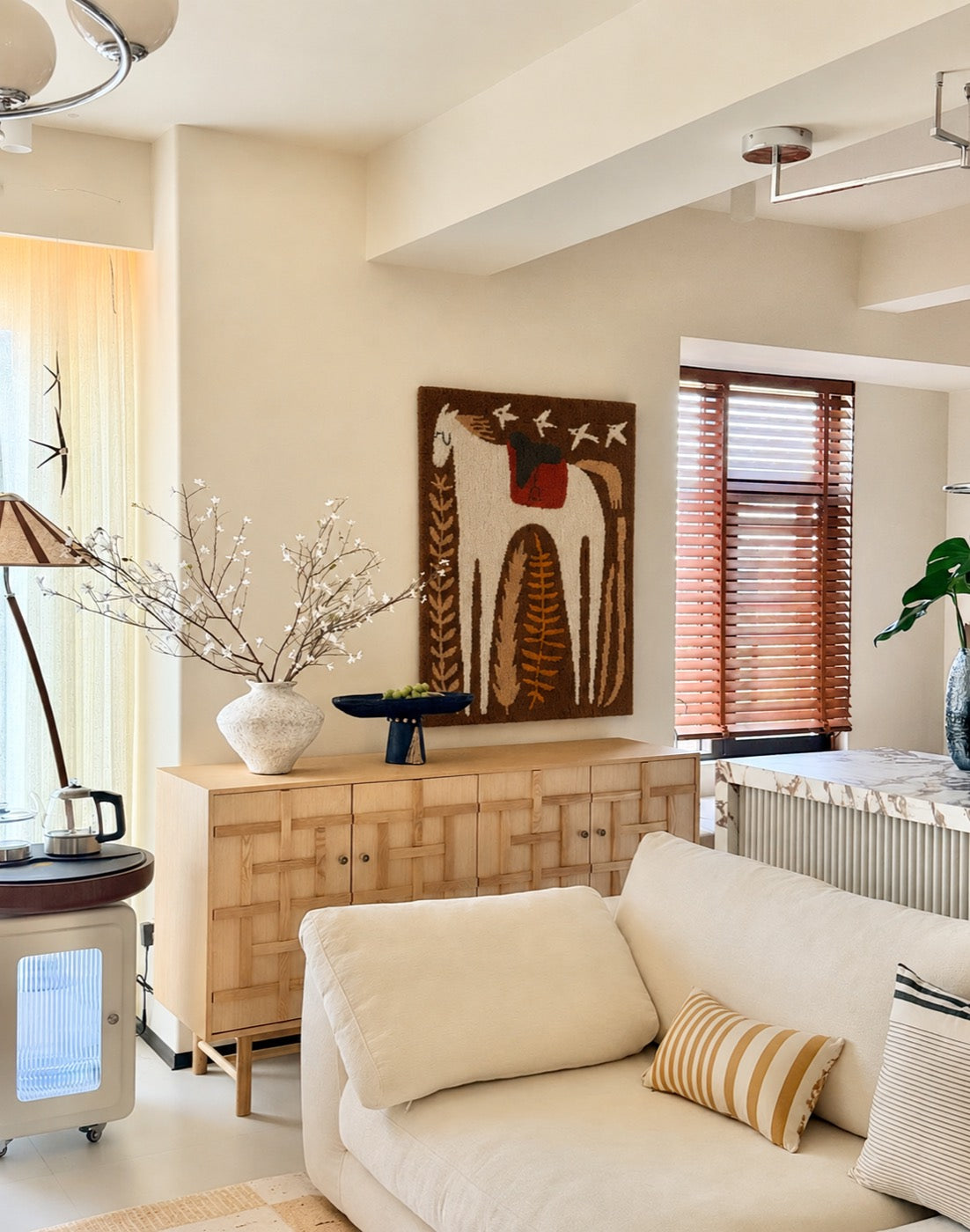 A hand-tufted wool folk horse tapestry in cocoa, cream and rust hung above a woven-front oak sideboard