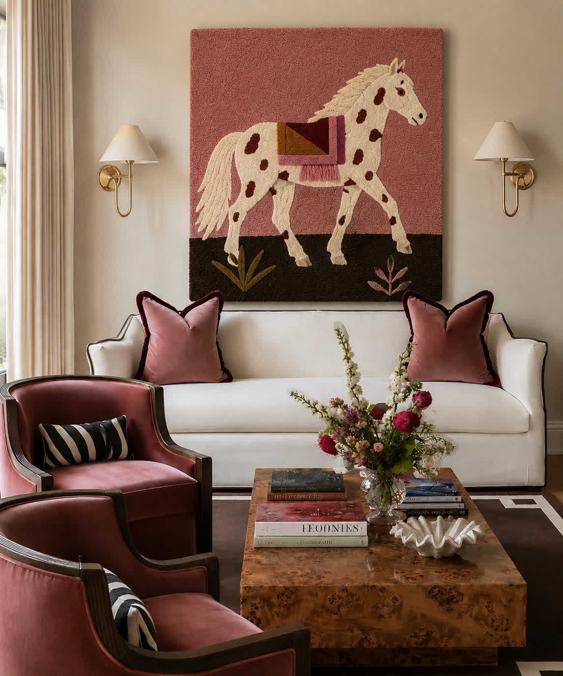 A hand-tufted wool dappled horse panel on a rose ground hung between brass sconces above a white sofa