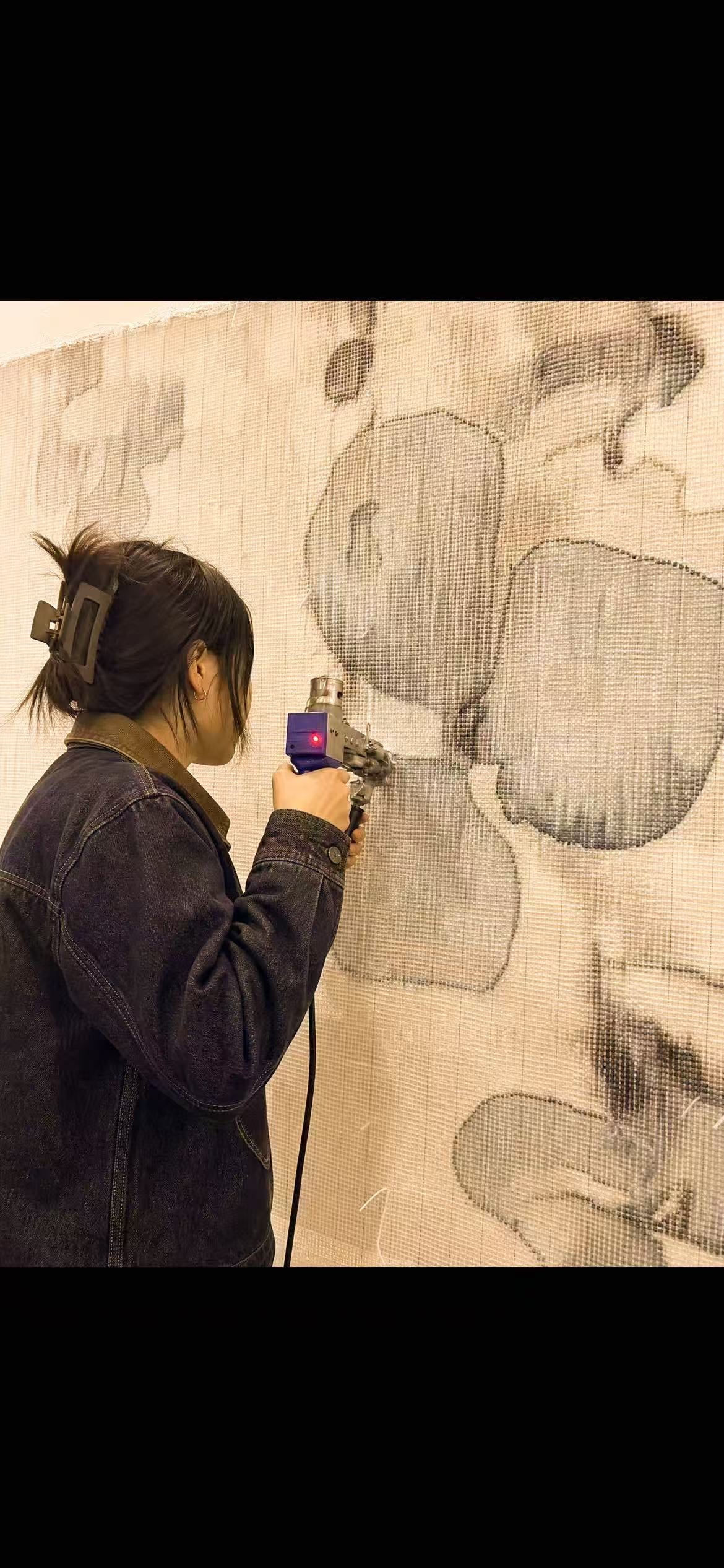 Close-up of a maker guiding a tufting gun across a floral wool panel