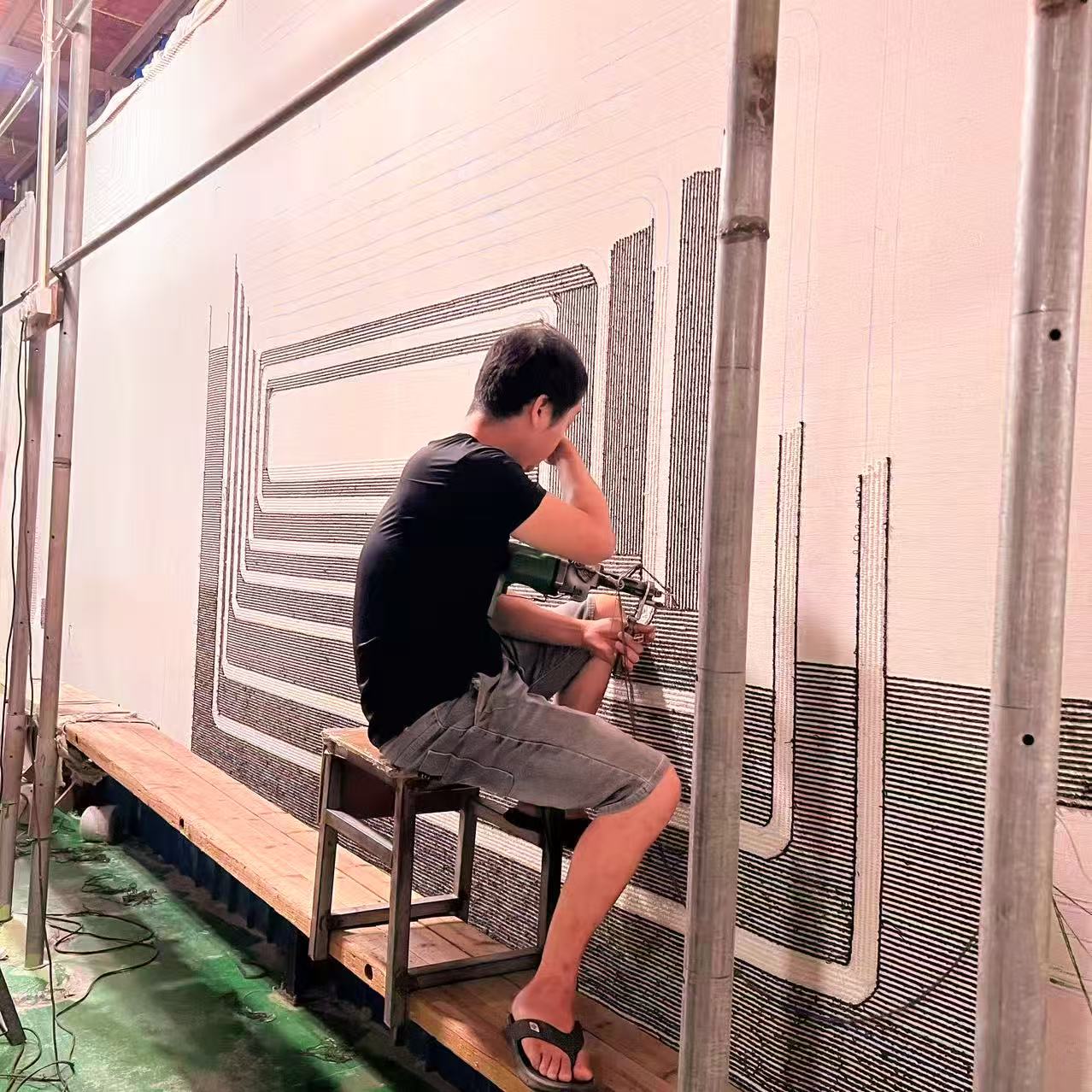 A maker hand-tufting a large sculptural wool panel on the production floor
