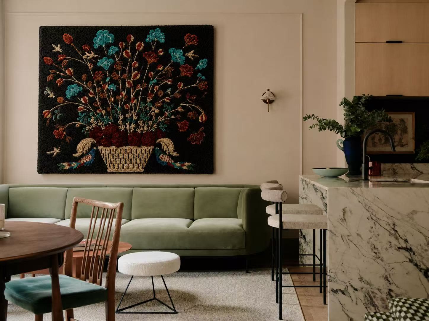 A Hewn Earth floral wall tapestry hung above a green velvet sofa in a designer's interior