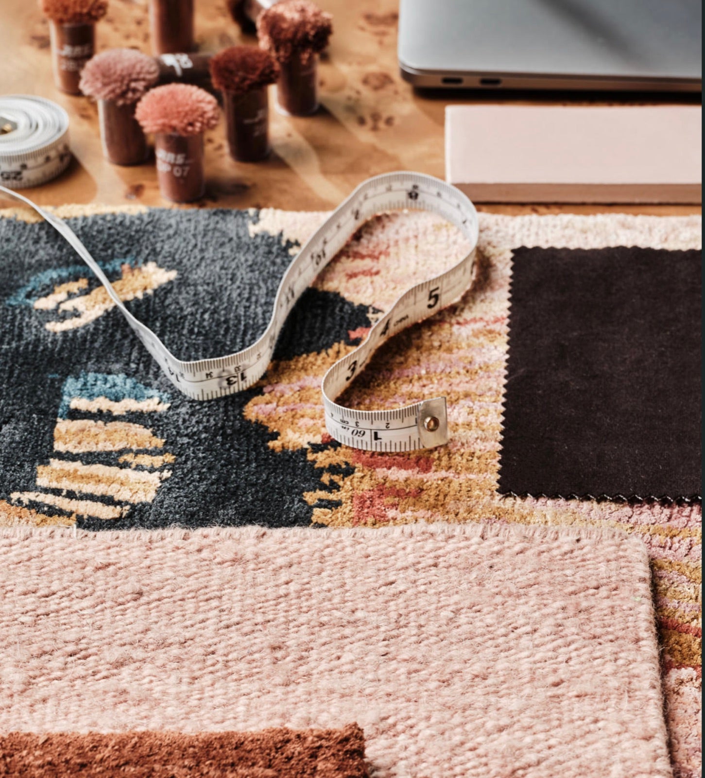 Wool colour tufts, a tape measure and rug swatches on a designer's desk